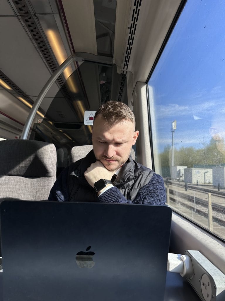 GET BLOGGED Man working on laptop while travelling by train, with sunlight through the window