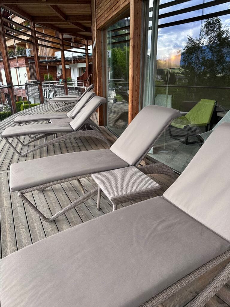 Wooden balcony with loungers and a hanging chair overlooking the mountains at Leitlhof Hotel in South Tyrol.