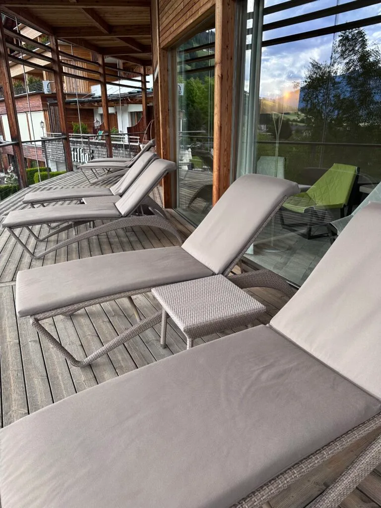 Wooden balcony with loungers and a hanging chair overlooking the mountains at Leitlhof Hotel in South Tyrol.