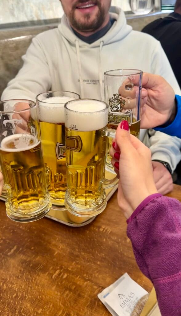 Group of people toasting with glasses of beer at a wooden table.