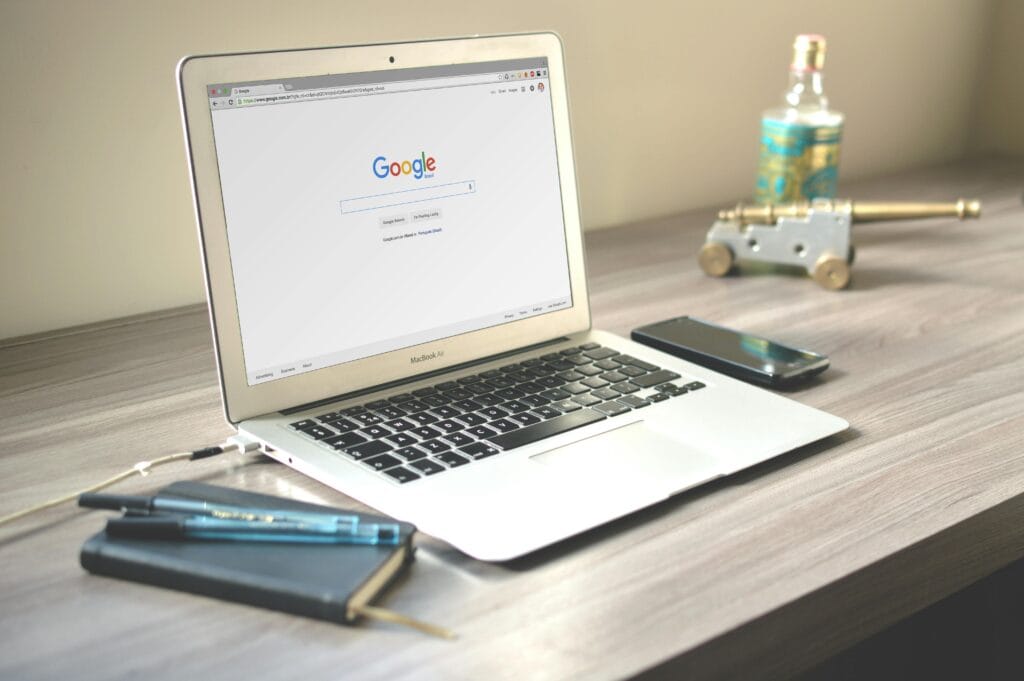 Open MacBook Air on a desk displaying Google Search page