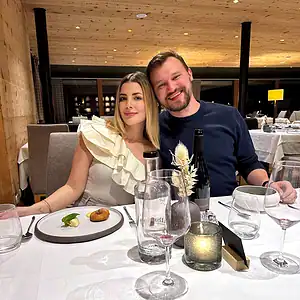 Couple seated at a restaurant table enjoying a fine dining experience with wine and plated dishes
