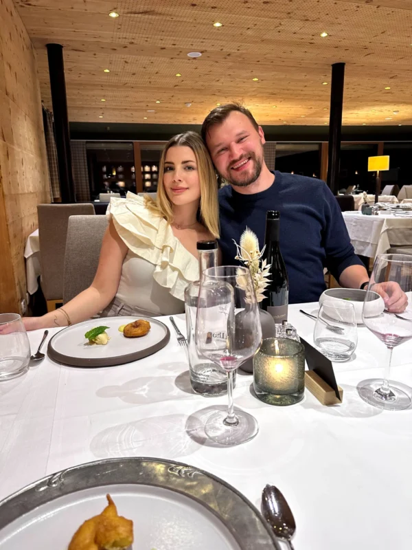 Couple seated at a restaurant table enjoying a fine dining experience with wine and plated dishes