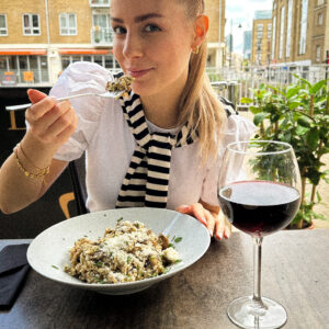 Girl eating risotto at a restaurant terrace in London.