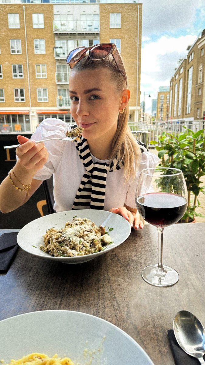 Girl eating risotto at a restaurant terrace in London.