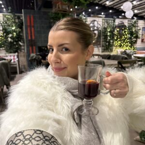 Woman enjoying a warm beverage in a festive setting.