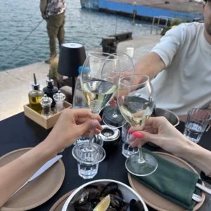 Enjoying seafood and wine by the harbour with friends in a scenic waterfront setting.