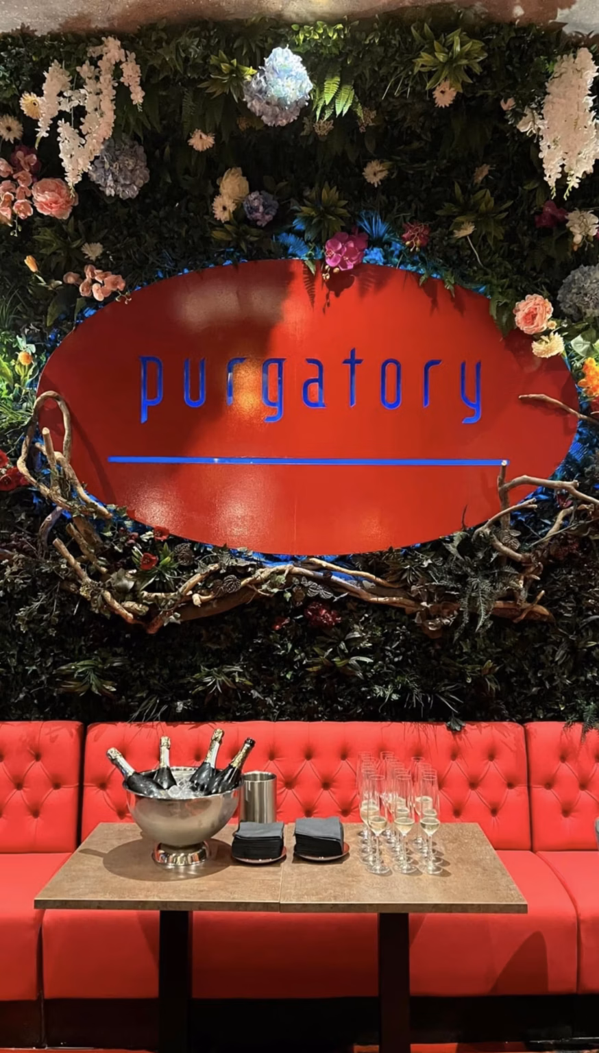 The Purgatory Bar sign, set in a wall of flowers