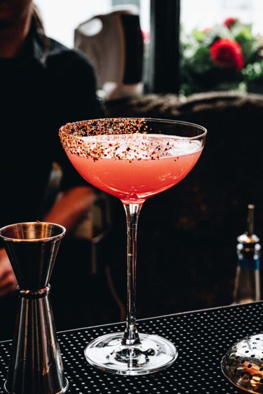 A red coupe cocktail with a chilli rim on the bar counter at Purgatory Bar