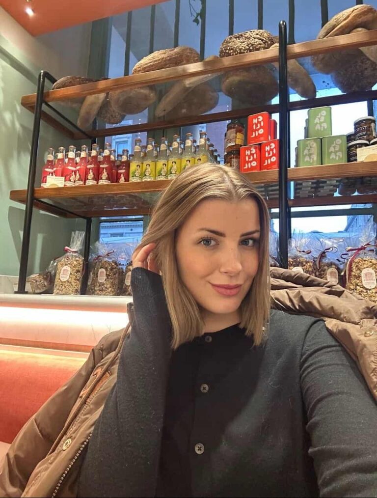 Velena Nikolova in a dark cardigan in front of deli shelves