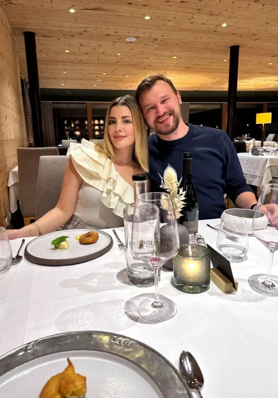Couple seated at a restaurant table enjoying a fine dining experience with wine and plated dishes